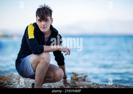 Portrait of a young handsome man sitting by the sea Stock Photo