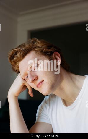 Young man resting his chin on his hand while looking at camera Stock Photo