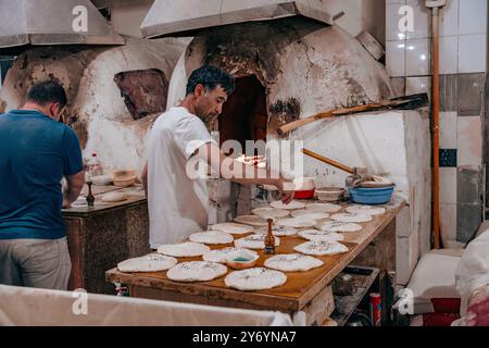 Two men are working in a bakery, one of them is making pizza dough Stock Photo