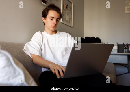 Young person focused while working on laptop at home Stock Photo