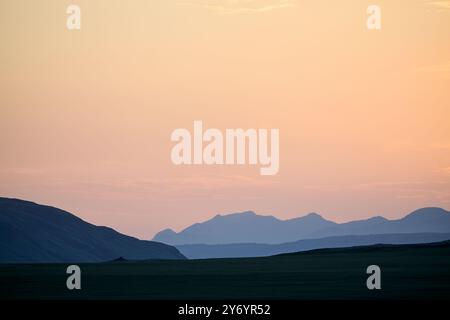Various mountains with ridges at sunset time against orange sky Stock Photo