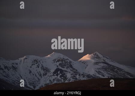 Frozen rocky formation against cloudy dark sky Stock Photo