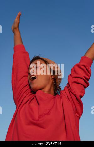 Smiling happy woman against blue sky background. Stock Photo