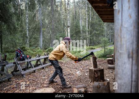 man chopping firewood with an axe for making a fire in the forest Stock Photo