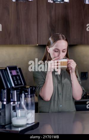 Female enjoying of fresh coffee aroma after brewing coffee using coffee maker in the kitchen at home. Stock Photo