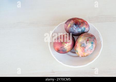 Three Easter eggs painted in galaxy colors on the white plate Stock Photo