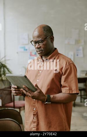 Vertical shot of African American businessman using huge tablet in office Stock Photo