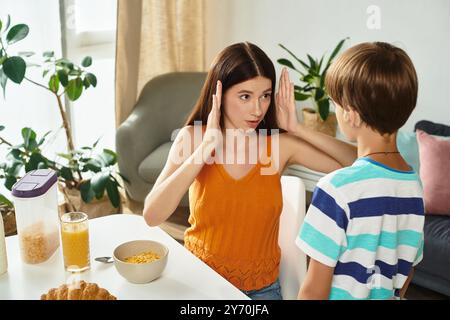 A devoted mother engages with her son using sign language at their breakfast table. Stock Photo