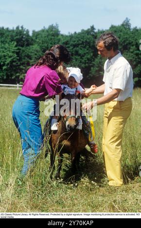 Carl XVI Gustaf, King of Sweden and family 1983. The King Carl XVI Gustaf, Queen Silvia and their children, crown princess Victoria and princess Madeleine on the ground of Solliden castle on Öland. The children are riding a small horse. Stock Photo