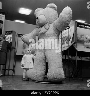 GIANT TEDDY BRIGHTON ;  Two year old Heather Sayers stares in awe at a giant six foot tall teddy bear - one of hundreds of toys on show at the British Toy Fair which opened here today.  Teddy is washable and can be bought by parents with big bank balances for £50.  28 January 1968 Stock Photo