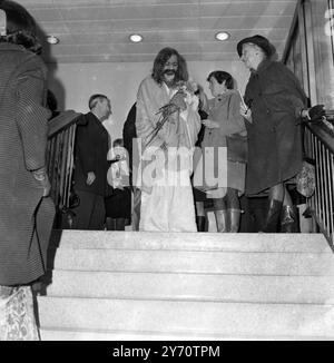 Clutching a handful of flowers on his arrival at London Heathrow Airport today , Maharishi Mahesh Yogi . Seen in the background (second left) is Mia Farrow , actress wife of Frank Sinatra who is reported to be going back to India with him to meditate . 24 January 1968 Stock Photo