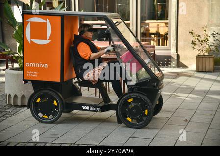 Pedal powered Omniva postal mail delivery EV vehicle Vok Bikes with storage for parcels, delivery in Old Town on cobblestone streets Tallinn, Estonia. Stock Photo