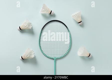White feather badminton shuttlecocks and two badminton rackets on light blue background. View from above. Concept racket sport. Leisure games. Stock Photo