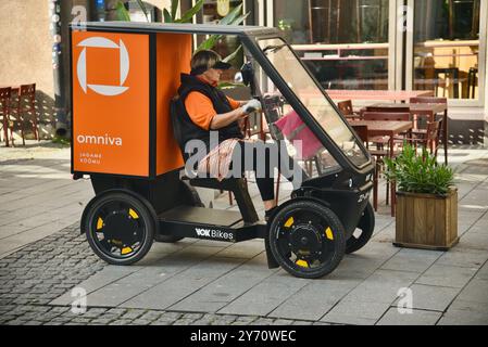 Pedal powered Omniva postal mail delivery EV vehicle Vok Bikes with storage for parcels, delivery in Old Town on cobblestone streets Tallinn, Estonia. Stock Photo