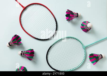 Colorful feather badminton shuttlecocks and two badminton rackets on light blue background. View from above. Copy space. Concept racket sport. Leisure Stock Photo