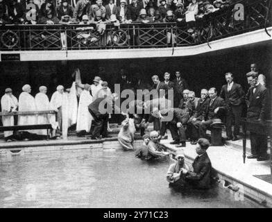 Baptism in public baths : A minister of the Bible Standard Church performing the rite by total immersion , at Calder Street Public Baths , Govanhill in Glasgow , Scotland . 16 June 1928 Stock Photo