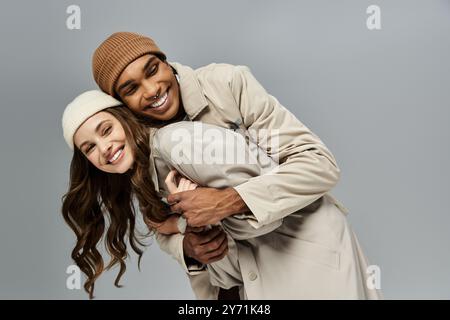 The couple shares a joyful moment, showcasing their chic autumn attire with playful affection. Stock Photo