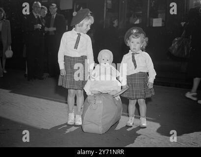 Lassies Leave Home   Leaving Waterloo Station on the first stage of their journey to Canada, aboard the Cunard-White Star liner 'Aquitania' boat train, is six-year-old June Higgins, and two-and-a-half-year old Avril Higgins of Edinburgh, who will join their Daddy in Edmonton. He emigrated six months ago.    Picture shows: 'Wee three' - June and Avril Higgins keep a safe hold on Dolly, as they prepare to leave Waterloo Station this morning (Tuesday). Avril seems a little worried about the journey, judging by her expression.    June 15 1948 Stock Photo