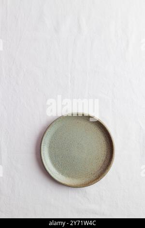 Empty rustic vintage green plate on a white tablecloth with copy space as a background for meal food dishes, food mock-up Stock Photo