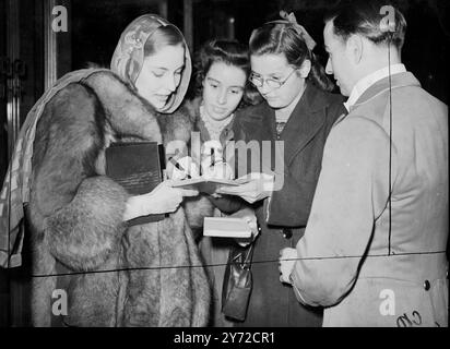 The stars were out tonight. There were huge crowds in Leicester Square tonight (Thursday) to watch American and British film stars arrive at the Odeon Theatre for the premiere of 'Ivy'. The film, a Universal International production, stores Joan Fontaine, Herbert Marshall, Richard Ney and Patric Knowles.  Photo shows, Valerie Moeson, warmly clad in furs and wearing a flowing silk headscarf, signs autographs for admirers at tonight's premiere.   25 September 1947 Stock Photo