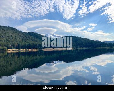 Lenticular clouds over Mount Shasta are reflected in the still water of Lake Siskiyou Stock Photo