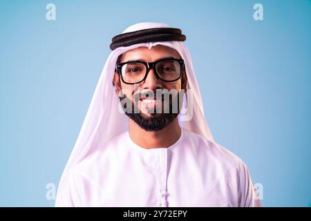 Arab businessman wearing emirati kandura portrait in studio in Dubai - Handsome middle eastern male adult posing on cut-out background - Muslim bearde Stock Photo
