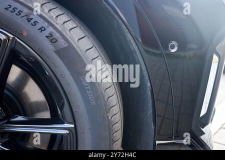 Selective focus on right side of front bumper decorative element side parking sensor of luxurious car bumper closeup with R20 wheel and alloy rim Stock Photo