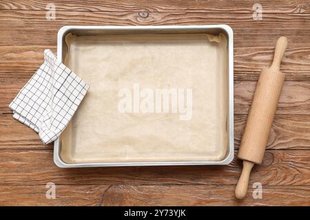 Empty baking tray, rolling pin and napkin on wooden background Stock Photo