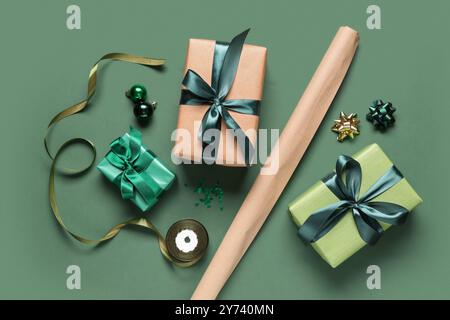 Christmas gift boxes with packing materials and different decorations on green background Stock Photo