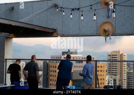 Beirut, Beirut, Lebanon. 27th Sep, 2024. People watch from a balcony as explosions sound across Beirut, and smoke rises from southern suburb on the old airport road near Burjlal Barajneh, near Palstinian Camp. (Credit Image: © Timothy Wolfer/ZUMA Press Wire) EDITORIAL USAGE ONLY! Not for Commercial USAGE! Stock Photo