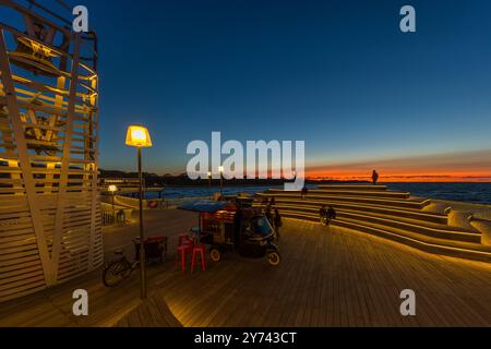 Tip of the Koserow pier, Usedom. The bridge is a wave-shaped construction 280 meters long into the Baltic Sea. The bridge is 3.50 meters wide and stands on 68 pillars. Built in 2021, sustainable tropical wood was used for the bridge decking. Blue hour on the modern Koserow pier on the island of Usedom. Seebrücke Koserow, Mecklenburg-Vorpommern, Germany Stock Photo