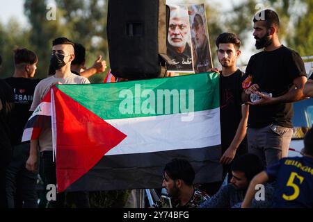 Mosul, Iraq. 27th Sep, 2024. Supporters of Kataeb Sayyid al-Shuhada armed faction (member of the Hashed al-Shaabi/Popular Mobilisation Forces or PMF) hold a Palestinian flag during a solidarity stand against the Israeli aggression on Lebanon and Palestine near the Great Mosque of Mosul in the city of Mosul. Credit: SOPA Images Limited/Alamy Live News Stock Photo