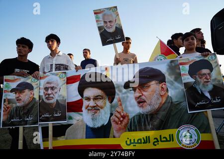 Supporters of Kataeb Sayyid al-Shuhada armed faction (member of the Hashed al-Shaabi/Popular Mobilisation Forces or PMF) hold a banner include portraits of Iran's Supreme Leader Ayatollah Ali Khamenei (R), Abu Ala al-Walai, head of the Kataeb Sayyid al-Shuhada (2-R), Hezbollah chief Hassan Nasrallah (C), Iraqi Popular Mobilisation Forces (PMF) commander Abu Mahdi al-Muhandis (2-L), during a solidarity stand against the Israeli aggression on Lebanon and Palestine near the Great Mosque (not in view) of Mosul in the city of Mosul, Iraq. Stock Photo