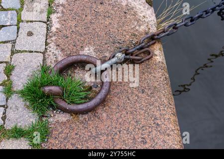 Rusty metal ring and chain attached to a stone dock Stock Photo