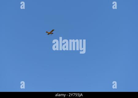 Small airplane flying high against a clear blue sky Stock Photo