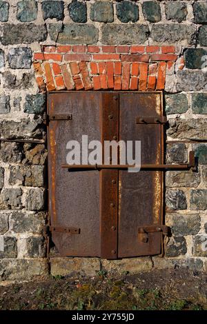 Rusty metal door on the stone wall of a historic charcoal oven at Taalintehdas (Dalsbruk) in Finland. Stock Photo