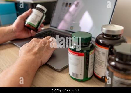 A technology use concept with a person using a laptop computer to search online for information and learn about health supplements. Stock Photo