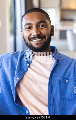 Smiling man in casual shirt relaxing indoors, enjoying diverse friends hangout, at home Stock Photo
