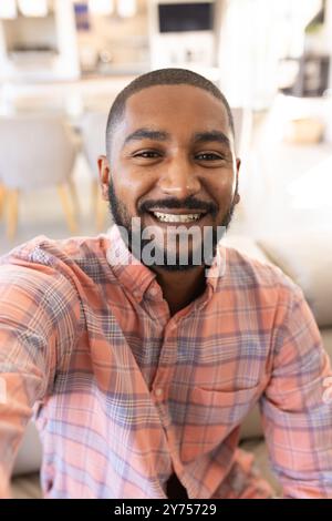 Taking selfie, smiling indian man in living room, on video call Stock Photo