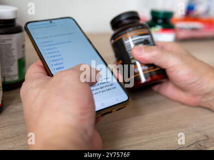 A technology use concept with a person using a mobile phone to search online for information and learn about health supplements. Stock Photo