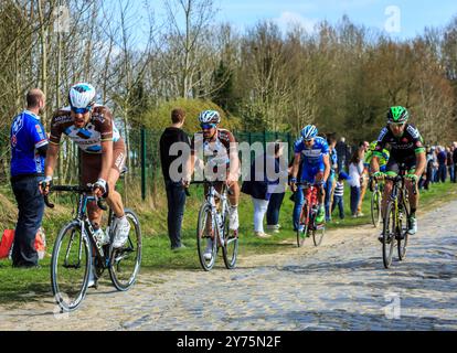 Carrefour de l'Arbre, France - April 12,2015: Image of a group of four cyclists riding in the famous sector Careffour de l'Arbre during Paris-Roubaix Stock Photo