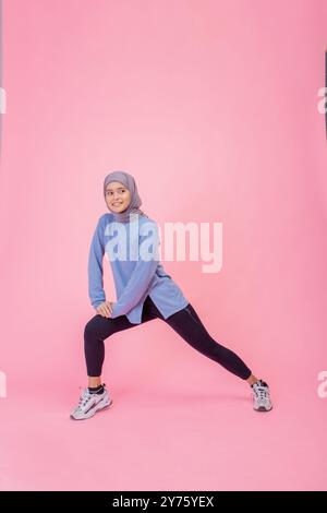 A Dynamic and Energetic Young Woman in Trendy Activewear Posing Confidently Against a Bright Pink Background Stock Photo