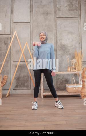 Active Young Woman in Sports Attire Using Dumbbells in a Modern Gym Setting Stock Photo
