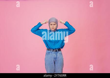 A Confident Young Woman Dressed Fashionably in a Hijab Posing Beautifully Against a Pink Background Stock Photo