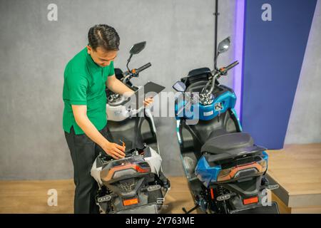 asian engineer fixing electric motorcycle using tools Stock Photo