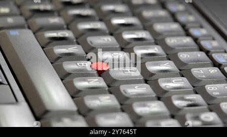 Laptop keyboard with a red track point in the middle, shallow depth of field closeup, computer keys background. Soft focus keys, writing, typing job a Stock Photo