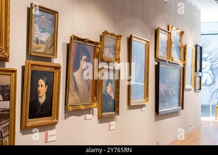 Various different paintings in gold gilded frames hanging on the wall in the Museum of Opole Silesia, Poland, side view, closeup, museum hall, nobody. Stock Photo