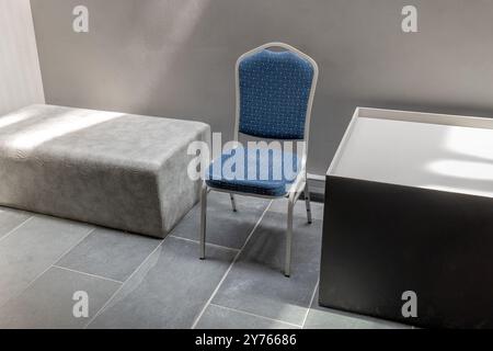 One single empty chair in a modern architecture interior corporate office, museum lobby space, waiting room abstract composition arrangement, sunlight Stock Photo