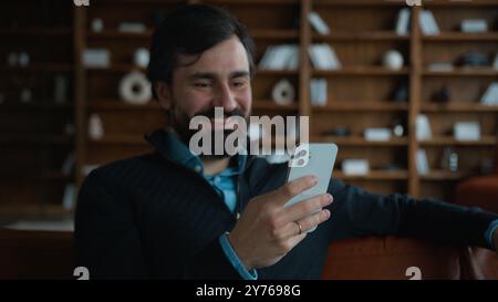 Happy smiling Caucasian middle aged businessman male client entrepreneur using mobile phone online app laughing worker man use social media raising Stock Photo