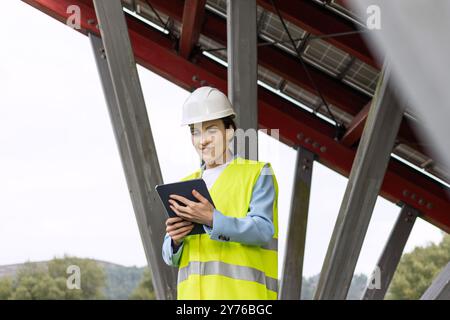 Female Solar energy engineer working outdoor on ecological solar farm construction. Renewable clean energy technology concept Stock Photo